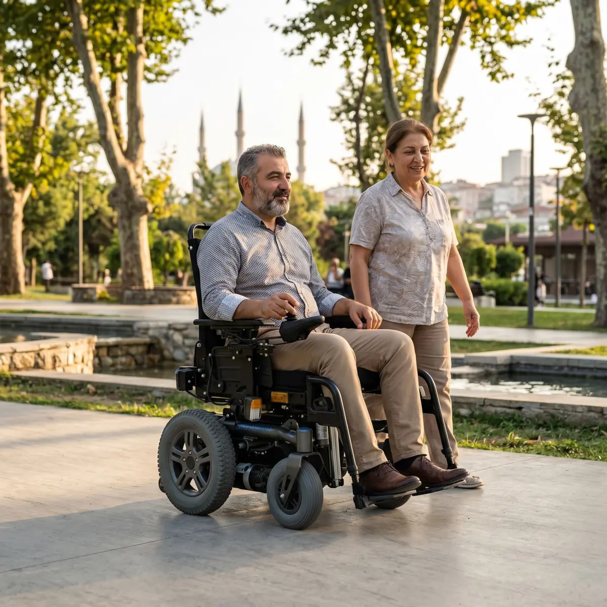 Parkta modern akülü sandalye kullanan bir kişi ve yanında yürüyen yakını